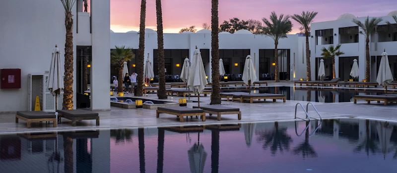 Piscina d’hotel circondata da palme al tramonto