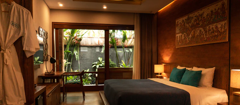 Camera d’hotel con letto in legno e cuscini verde acqua