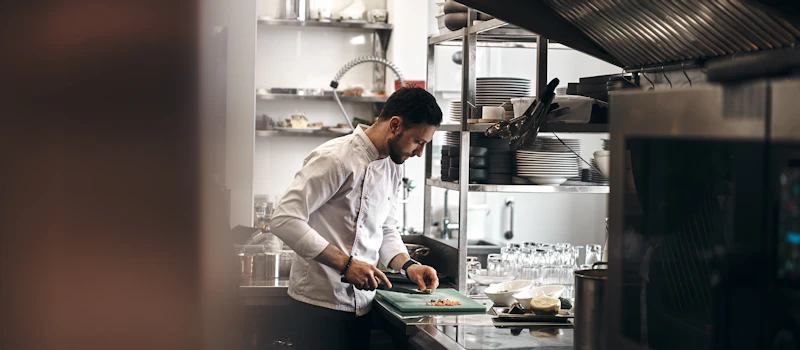 Restoran mutfağında sebze doğrayan aşçı